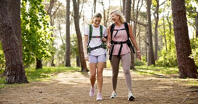 Buy stock photo Mother, daughter and hiking in forest with laughing for fitness adventure, sightseeing and explore nature. Backpack, mature woman and girl in woods with walking, holiday travel and bonding with joke