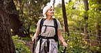 Mature woman, hiking and forest with walking sticks for adventure, sightseeing or travel in nature. Female person, hiker or tourist with backpack or equipment for outdoor trekking journey in woods