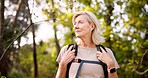 Mature, woman and hiking in forest with backpack for fitness adventure, sightseeing and explore nature. Trekking, person and thinking of scenery in woods with walking, holiday travel and cardio hobby