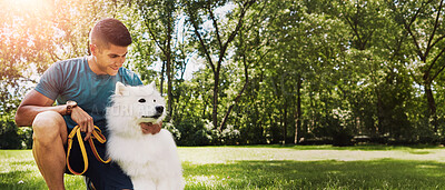 Buy stock photo Shot of a handsome young man walking his dog in the park