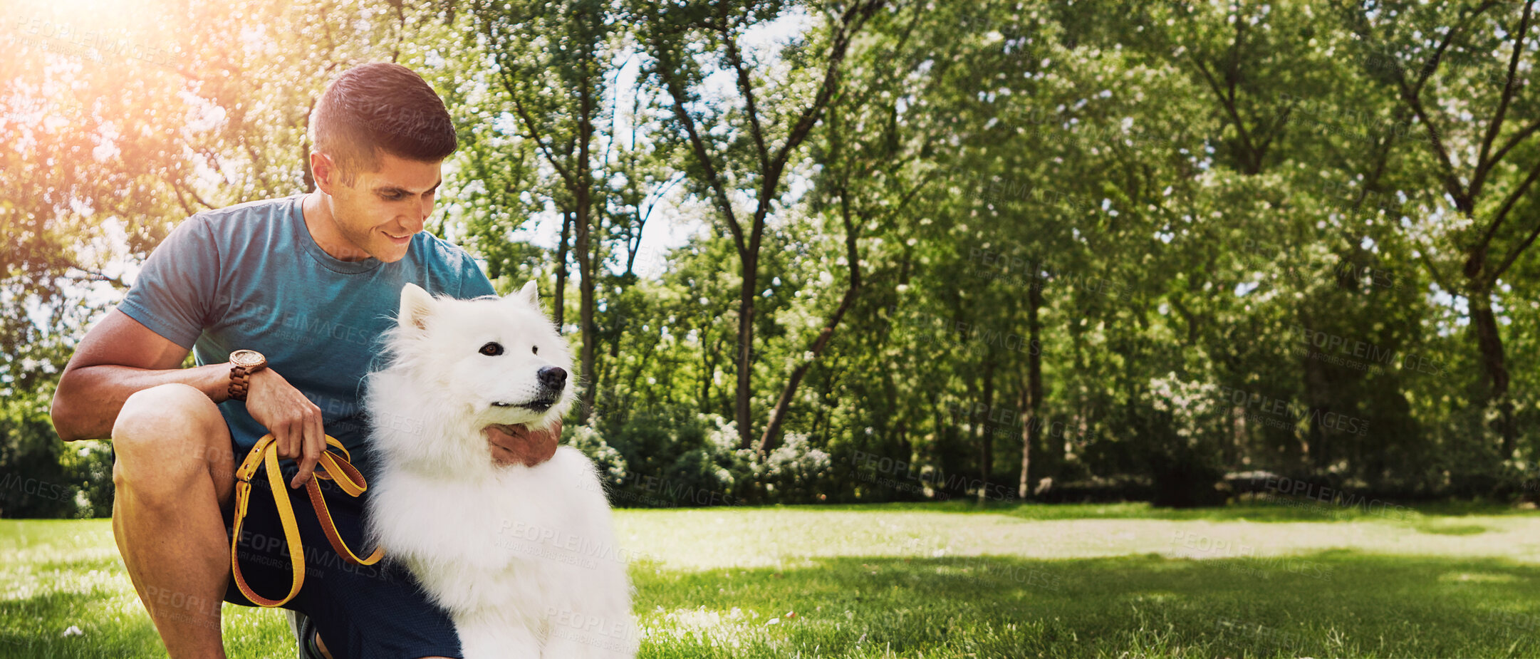 Buy stock photo Shot of a handsome young man walking his dog in the park