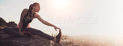 Buy stock photo Shot of a sporty young woman stretching outdoors