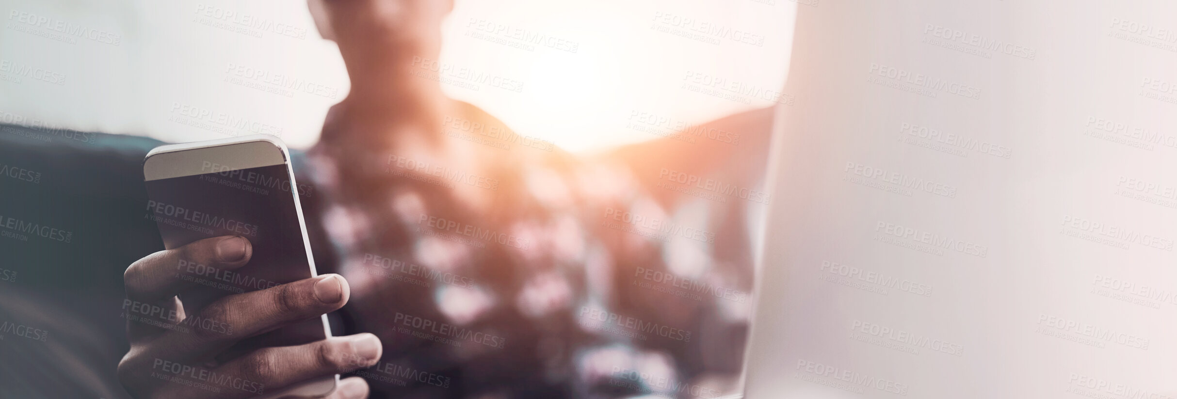 Buy stock photo Shot of a young man using his laptop and cellphone while sitting on the sofa at home