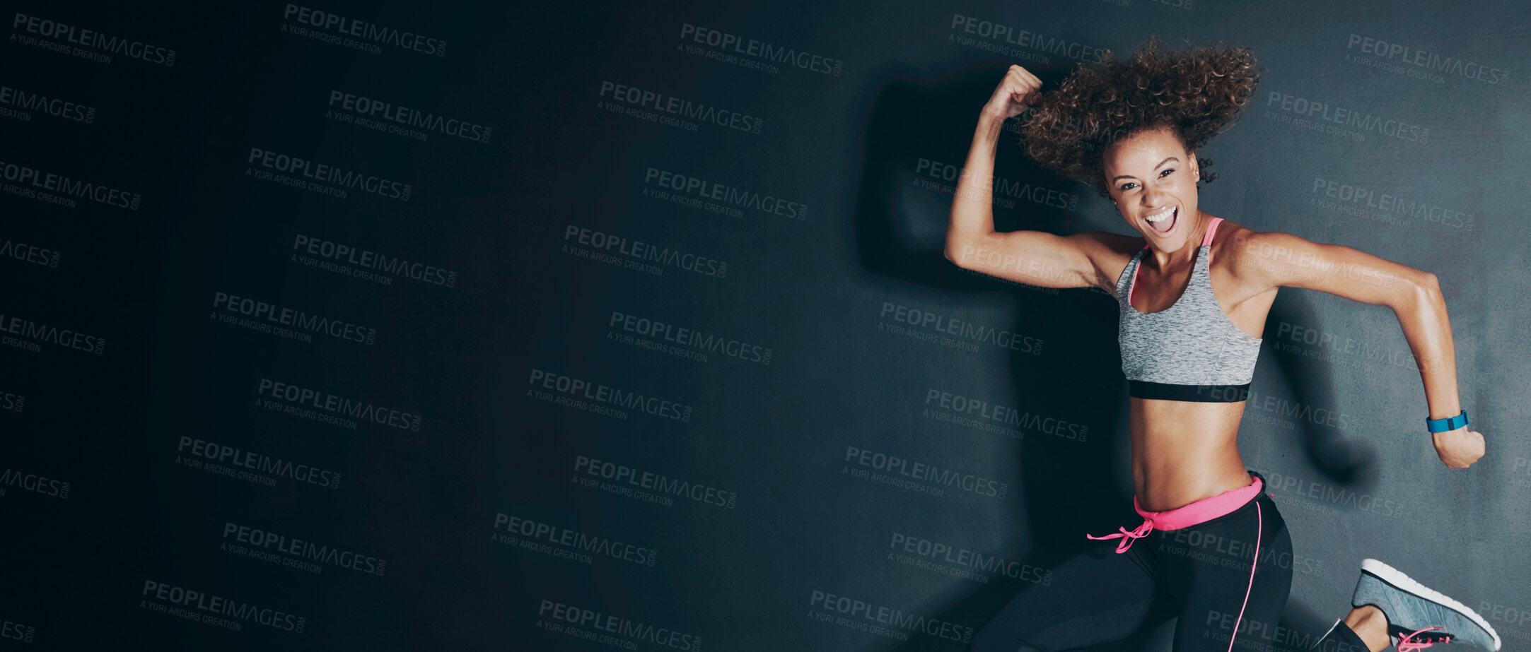 Buy stock photo Shot of a young woman flexing her muscles while jumping against a grey background