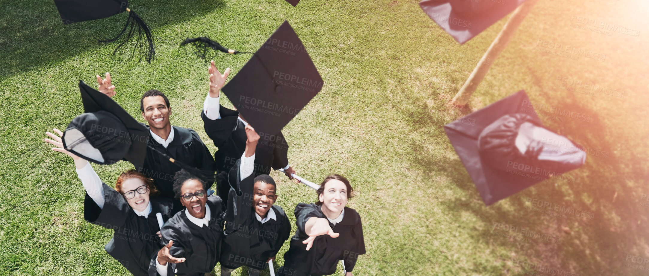 Buy stock photo High angle shot of a group of students throwing their caps into the air on graduation day