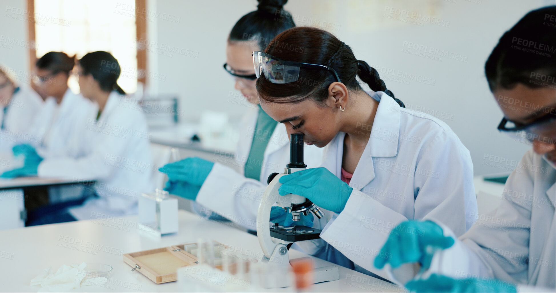 Buy stock photo Students, girl and microscope in science classroom for chemistry analysis, sample study or practical lesson. High school, people and learning of medical research for experiment with ppe safety in lab