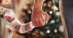 Christmas, holding hands and parents with kid in home for holiday, vacation and festive season. Family, love and closeup of child for celebration, party and tradition with decoration in living room