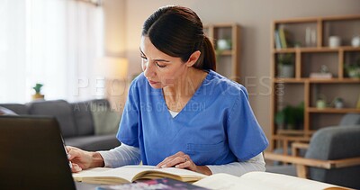 Buy stock photo Nurse, woman and studying with books at desk for medical research, information and knowledge. Home, healthcare and reading with laptop in living room for diagnosis reference, guide and treatment plan