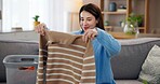 Laundry, housework and woman on sofa with smile, washing basket and home management in living room. Housekeeping, chores and happy housewife on couch folding fresh clothes, cleaning and morning care