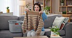 Laundry, cleaning and woman on sofa with smile, washing basket and home management in living room. Housekeeping, chores and happy housewife on couch folding fresh clothes, housework and morning care