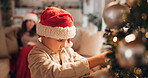 Christmas, bonding and child with ornaments, tree and decorations for holiday, hat and celebration. House, mom and boy in festive, together and season for family, relax and people in living room