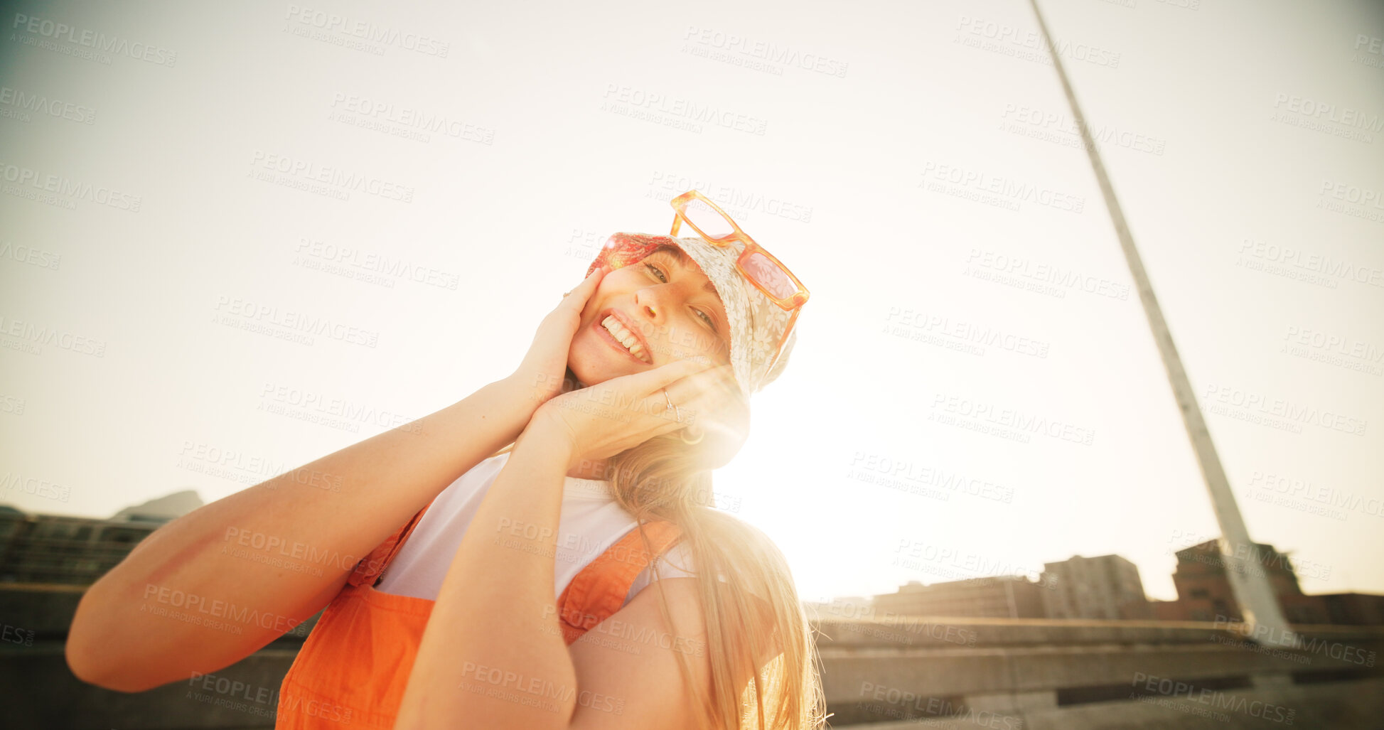 Buy stock photo Woman, gen z and fashion in city, summer and confidence with hands on face, hat and portrait on metro bridge. Girl, person and smile on road, sidewalk and sunshine in town with streetwear in Germany