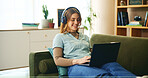 Laptop, headphones and woman on couch with online course, research or webinar in home. Elearning, relax and happy student girl on sofa with computer, web connection or music steaming in apartment