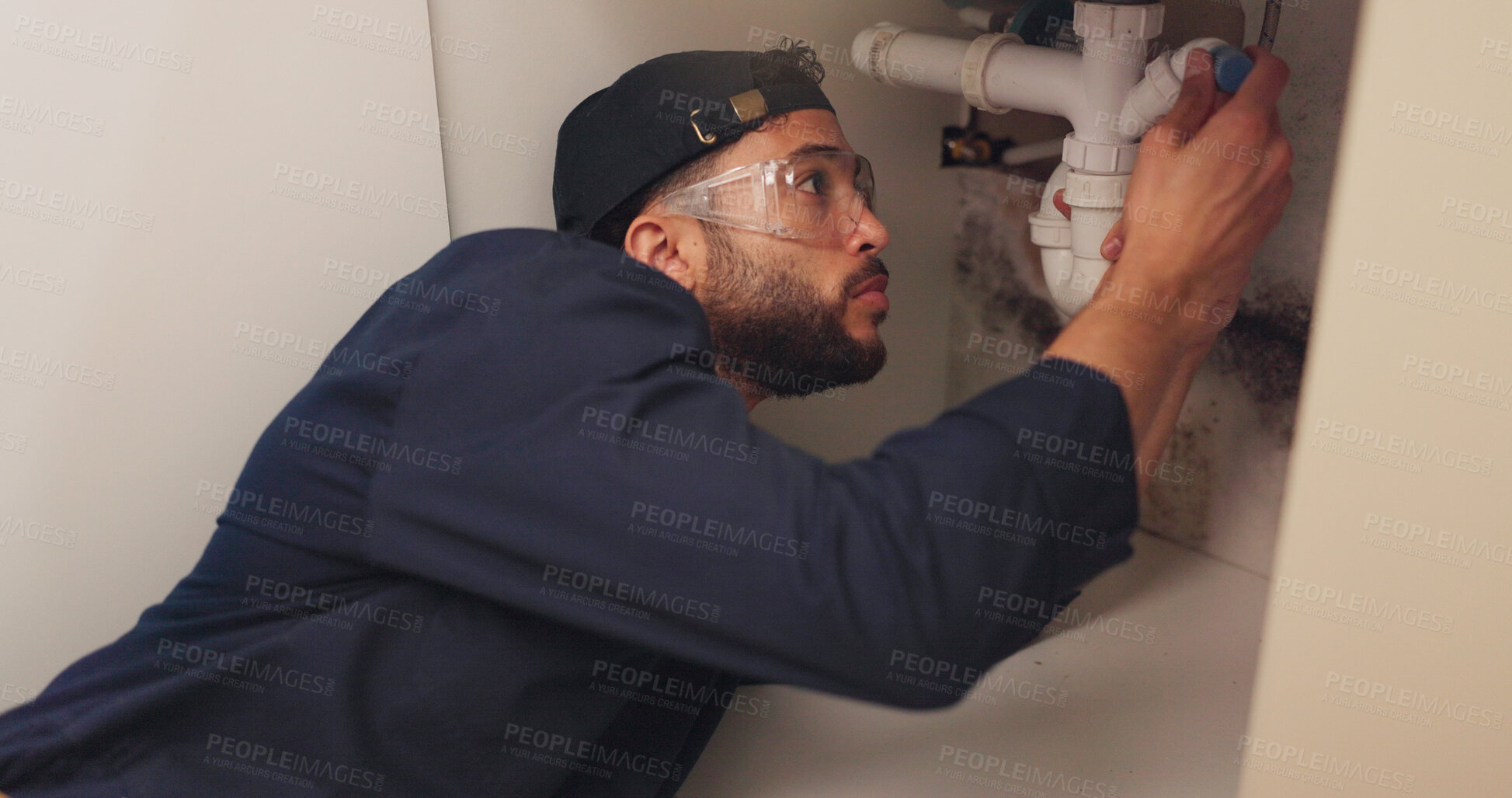 Buy stock photo Plumber, man and pipeline repair in kitchen with tools for home maintenance and fixing leak by sink. Plumbing contractor, handyman and working on filter system improvement for small business in house
