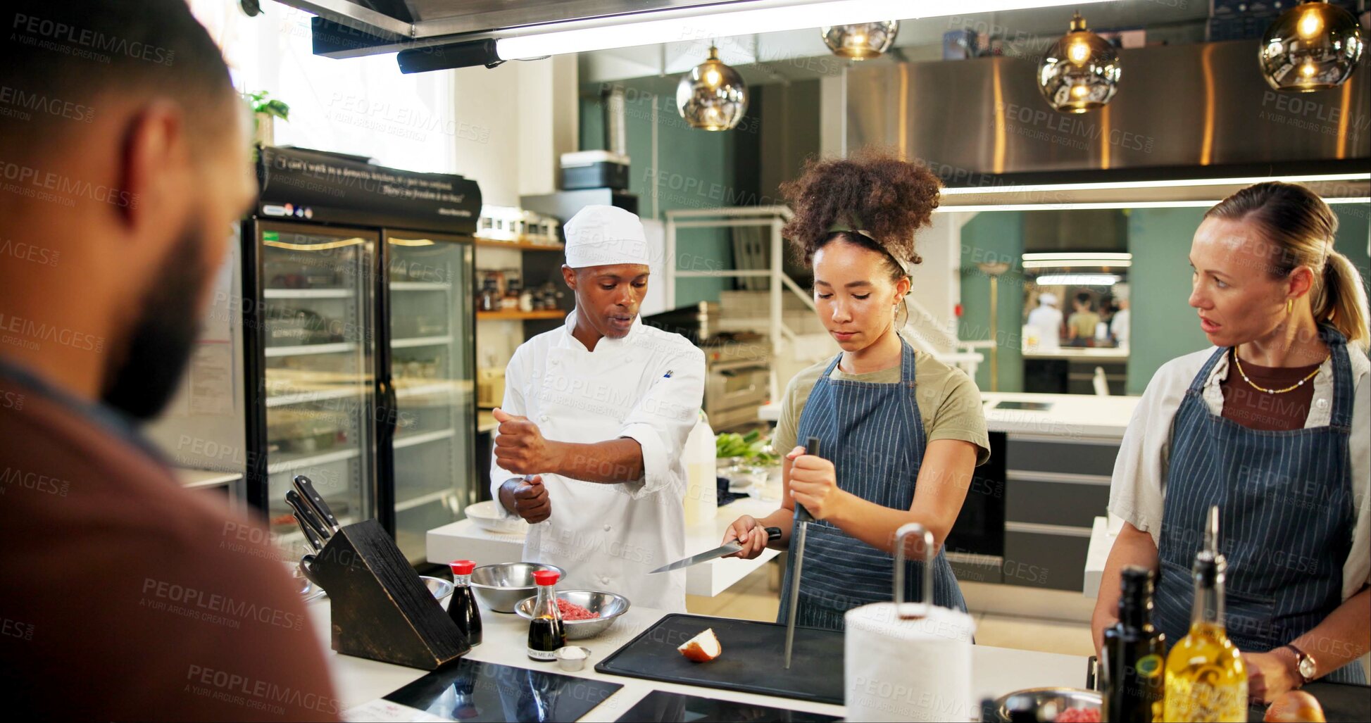 Buy stock photo Cooking, course and chef teaching people in kitchen for knife skills, cutting technique and learning. Culinary class, students and mentor with lesson on food preparation and education in hospitality