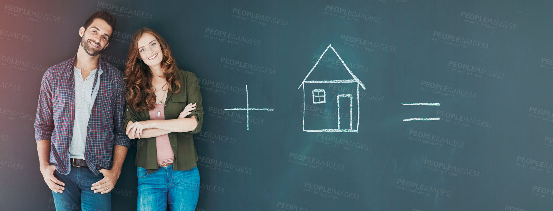 Buy stock photo Shot of a young couple standing in front of a blackboard with symbols written on it