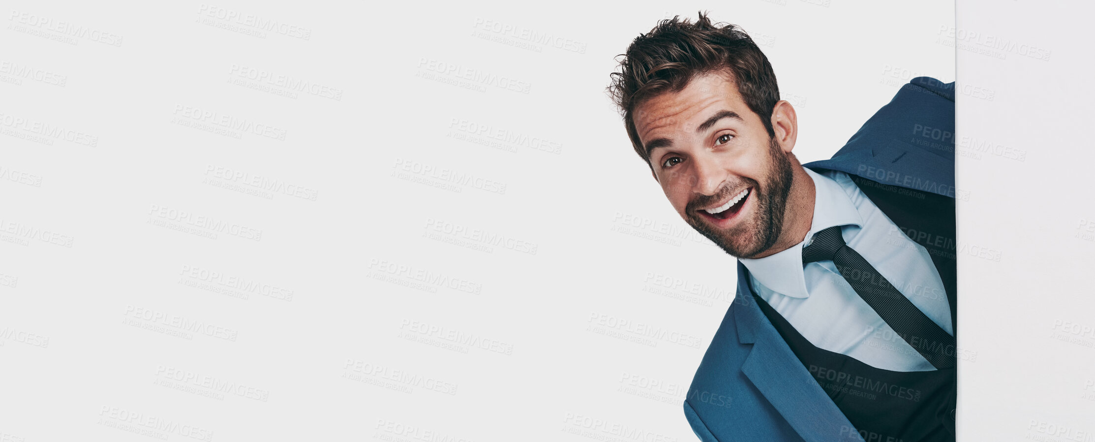 Buy stock photo Studio shot of a handsome businessman jumping out from behind a wall against a white background