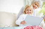 Girl, senior grandma and book in home living room with woman, smile and fantasy story for retirement bonding on sofa. Happy, elderly person and weekend for rest, family and lounge for memory on couch