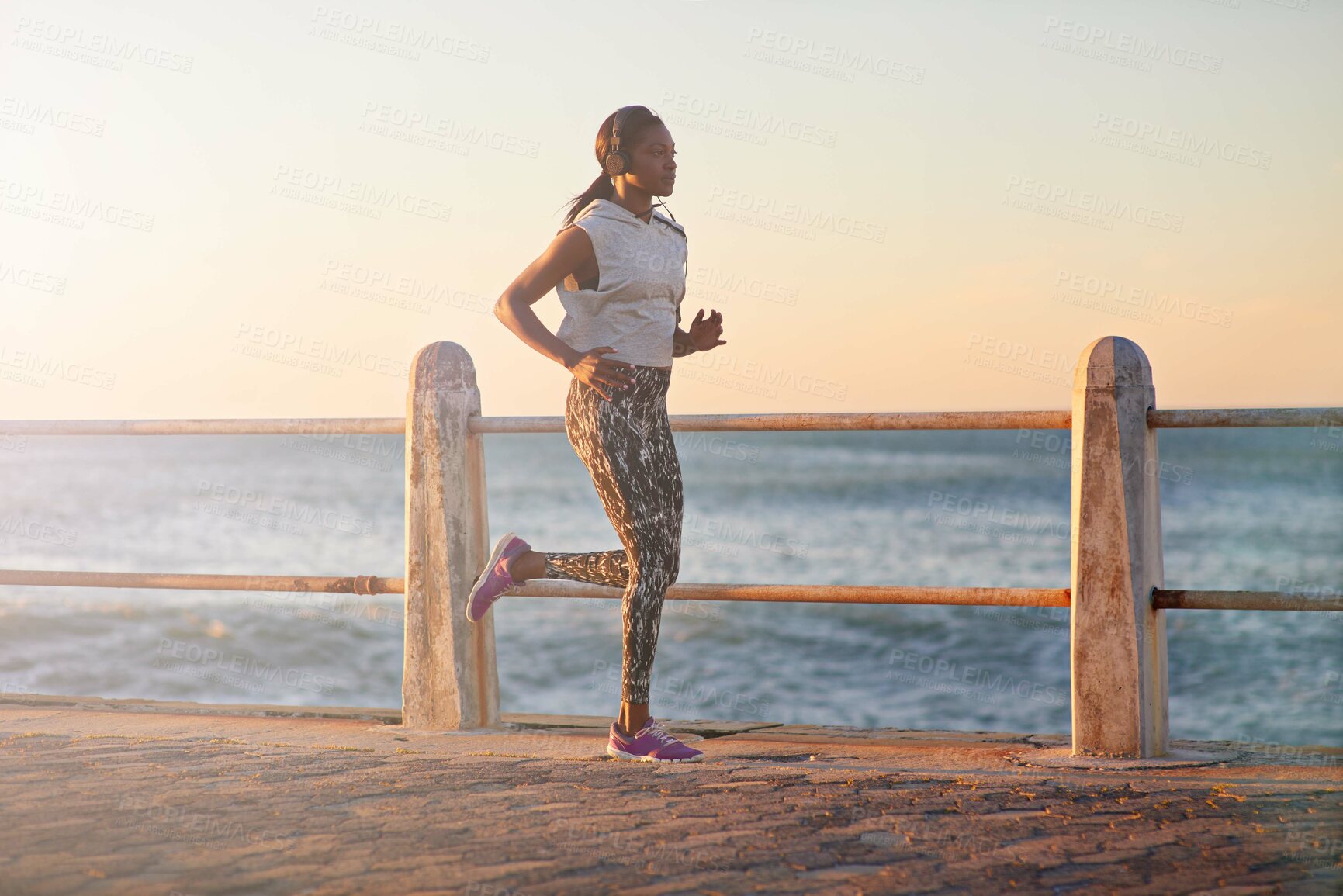 Buy stock photo Black woman, running or music at ocean for fitness, exercise or cardio training. Girl, headphones or jog on Mozambique promenade for wellness, challenge and lose weight goal with motivational podcast