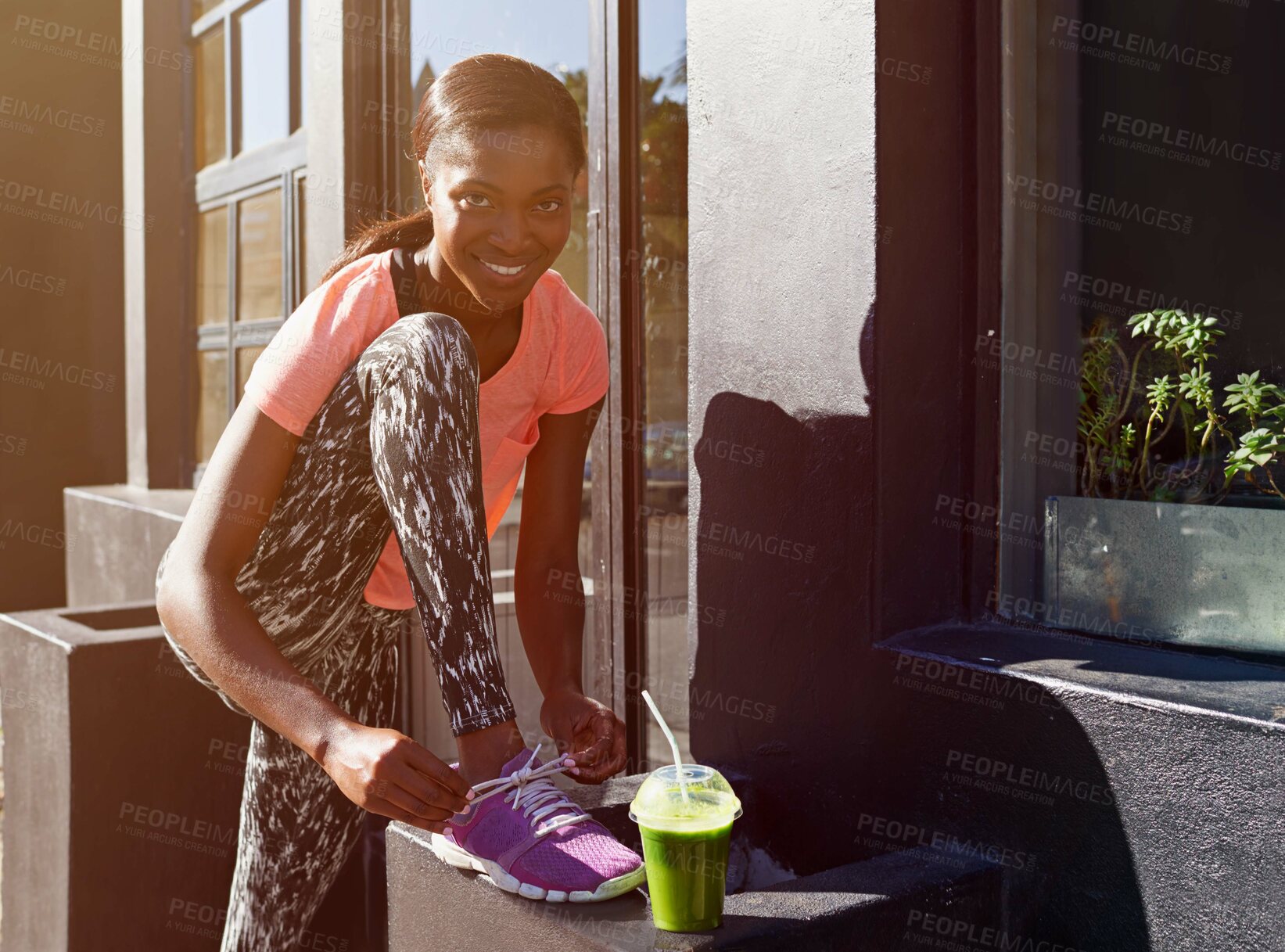 Buy stock photo Happy, portrait or black woman with tying shoe or smoothie for fitness, healthy diet or wellness in city. Young African, female person or runner with smile, drink or tie laces for workout preparation