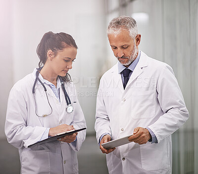 Buy stock photo Cropped shot of a mature doctor using his digital tablet to teach a female colleague