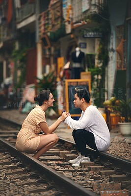 Buy stock photo Interracial couple, holding hands and train track in city for transportation, journey or vacation. Woman, man and travel on railway in town as holiday, adventure or outdoor fun on platform in Vietnam