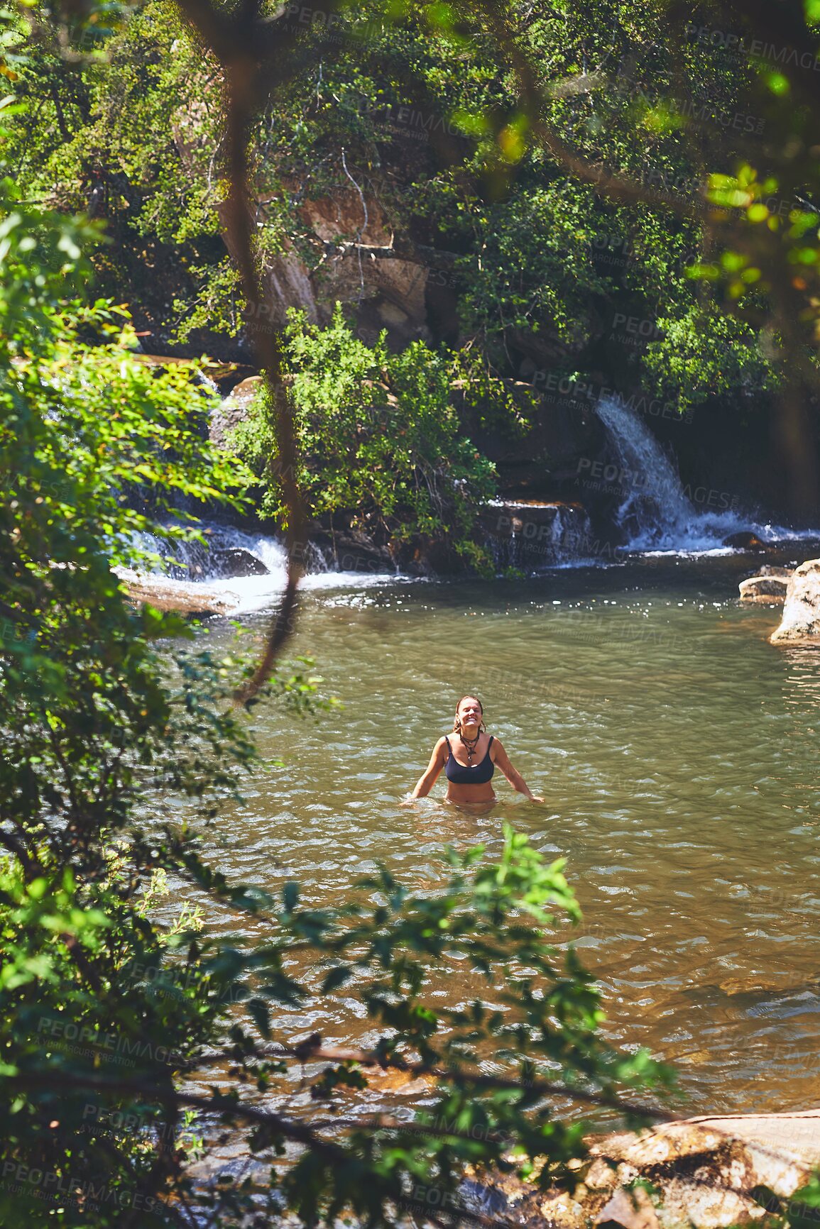 Buy stock photo Waterfall, happy and woman swimming on mountain for adventure at travel destination, nature and outdoors. Trees, journey and person relax in water, dam and stream for holiday, vacation and tourism