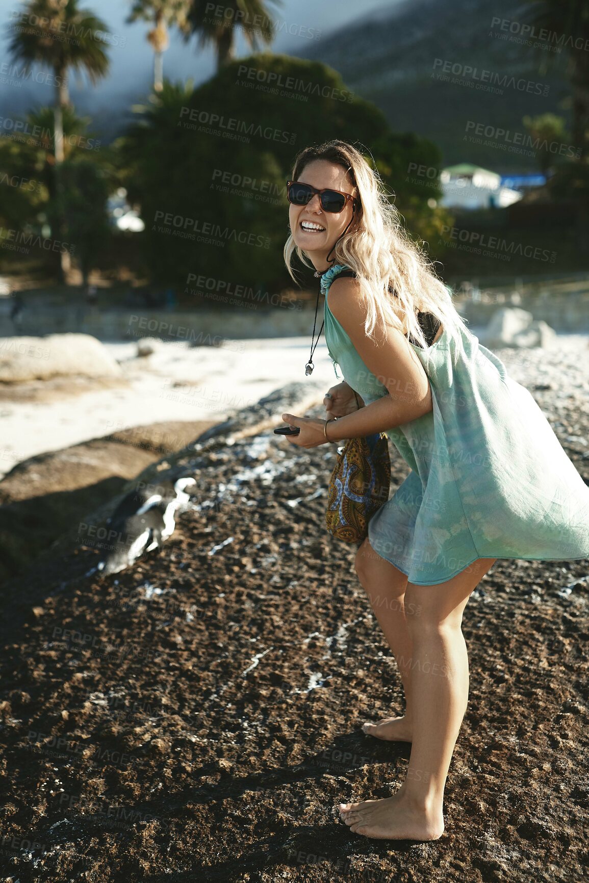 Buy stock photo Woman, sunglasses and happy on rocks at beach for travel adventure, summer holiday and weekend trip. Girl, person and smile by ocean for tropical vacation, exploring and sightseeing nature in Miami