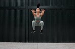 Full body fit and active mixed race woman jumping while working out alone outside. Focused and toned athlete doing cross fit and exercising downtown in a city. Physical activity and sports are healthy