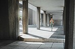 Young hispanic female athlete wearing headphones while running though a building outside. Young sportswoman focused on her speed, body, fitness and cardio health while training