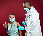 African american covid vaccinated woman showing thumbs up sign and symbol. Black doctor giving vaccine to patient wearing surgical face mask. Endorsing corona needle injection from physician in studio