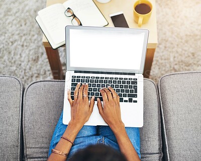 Buy stock photo Hands, screen and laptop above on sofa in living room with person or journalist working from home. Education, student and typing on keyboard with studying, notes and fingers on couch in house.