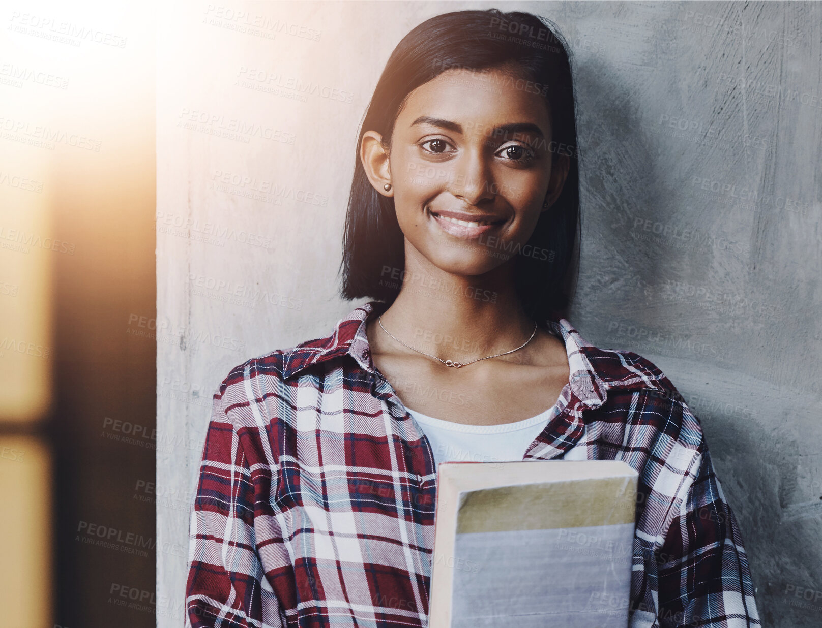 Buy stock photo Girl, university student and book in portrait by wall at business school, smile and education. Indian person, happy and studying for career in HR with research for industrial psychology at college
