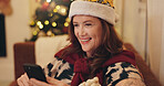 Happy, woman and relax with phone on Christmas for social media, update or online post at home. Santa hat, smile and female person with technology in living room for celebration, chat or festive text