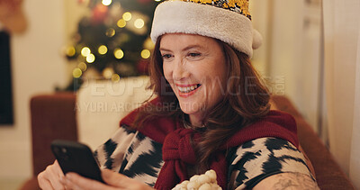 Buy stock photo Happy, woman and relax with phone on Christmas for social media, update or online post at home. Santa hat, smile and female person with technology in living room for celebration, chat or festive text