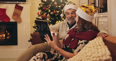 Buy stock photo Couple, happy and relax with tablet on Christmas for online shopping, platform and buying gift. Senior woman, man and talking with tech in living room of home for ecommerce, festive and celebration