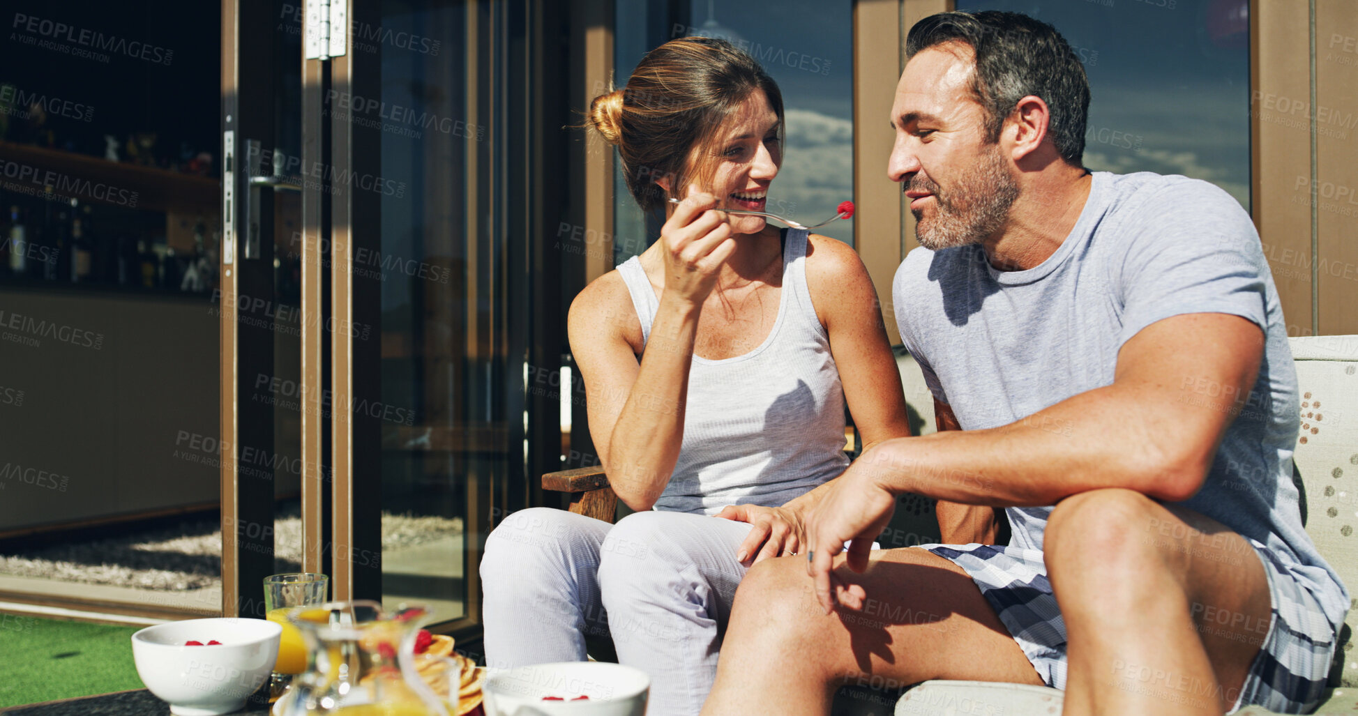 Buy stock photo Porch, couple and eating food with smile at hotel with happy people, fruit and room service. Morning, marriage and bonding together with feeding and anniversary trip on patio with summer travel