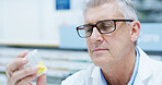 Senior man, pharmacist and bottle with reading, pills or info with thinking for wellness at store. Person, container and inspection at shop, dispensary or check label with product for health benefits