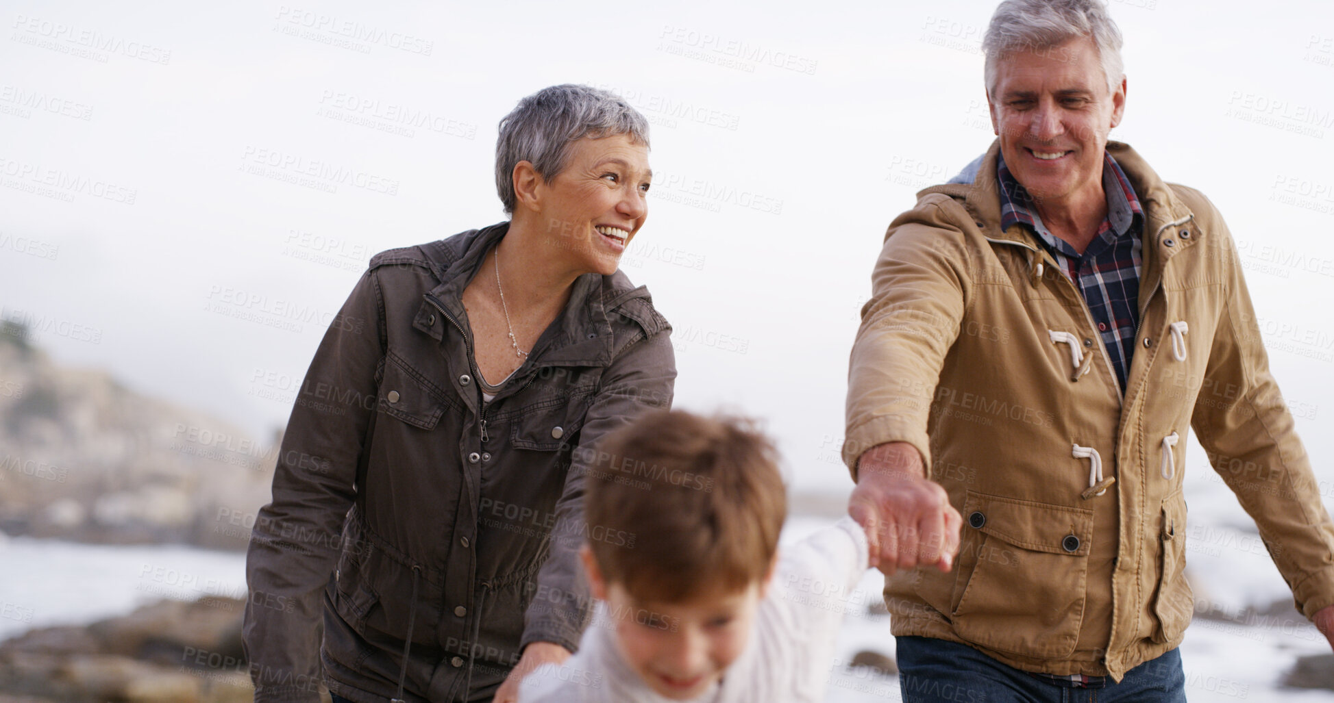 Buy stock photo Playing, ocean and grandparents with child holding hands for bonding, fun weekend and running at beach. Nature, family and young boy, grandpa and grandma on holiday, adventure and vacation together