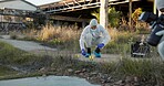 Crime scene, people and outdoor with equipment for forensics, evidence and investigation. Team, hazmat suit or photography in field for inspection, observation and documenting proof at police markers