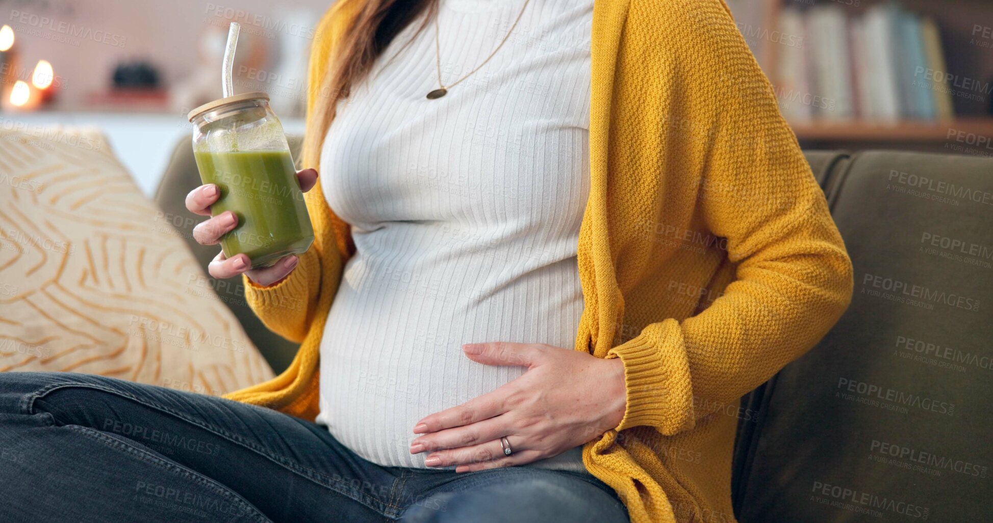 Buy stock photo Pregnant woman, hand and comfort with green smoothie for nutrition, digestive health and wellness on sofa. Future mother, stomach and person with health drink for diet vitamins or immune system boost