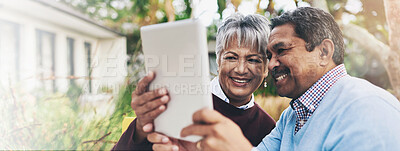 Buy stock photo Shot of an older couple using a digital tablet during a leisurely breakfast outdoors