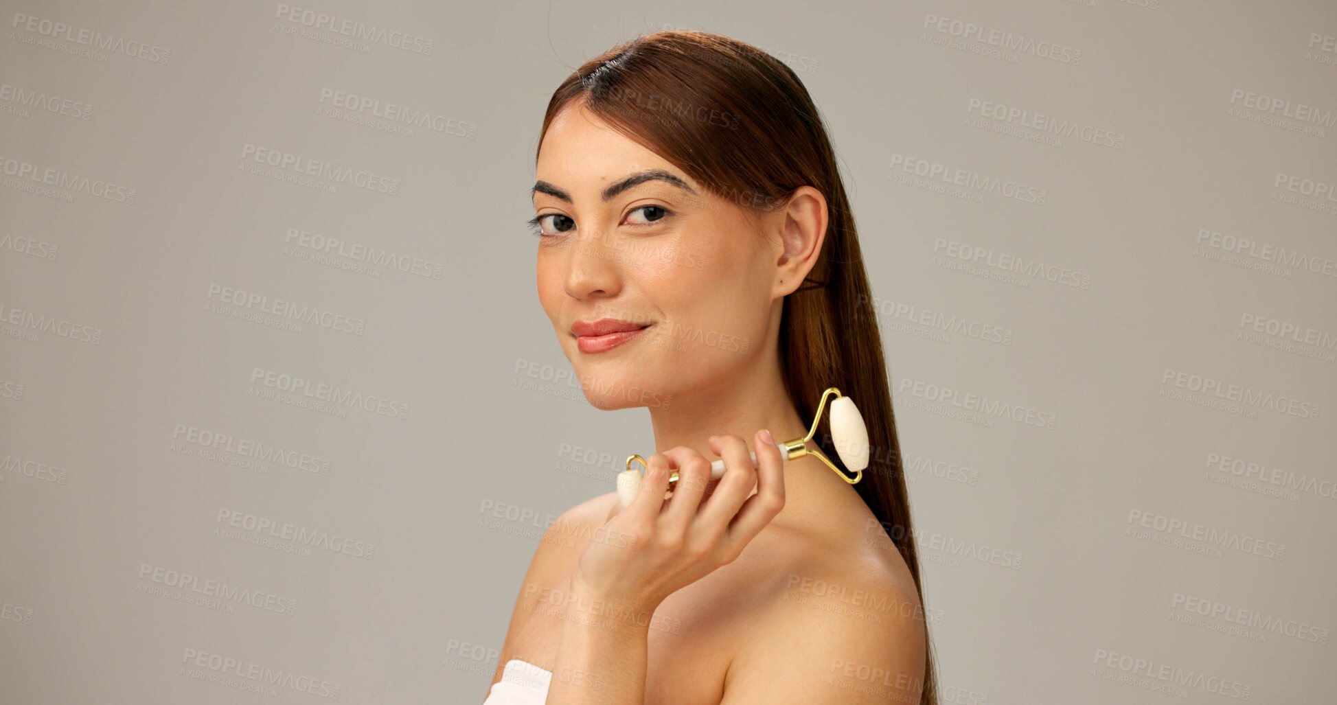 Buy stock photo Studio, woman and smile with roller for skincare on portrait for facial, beauty and firm skin on gray background. Female person, beautician and happy or confidence with routine, cosmetics and glow