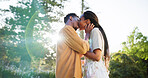 Morning, love and black couple in park kiss together for bonding, relationship and affection in nature. Lens flare, dating and man and woman outdoors for romance, embrace and commitment on weekend