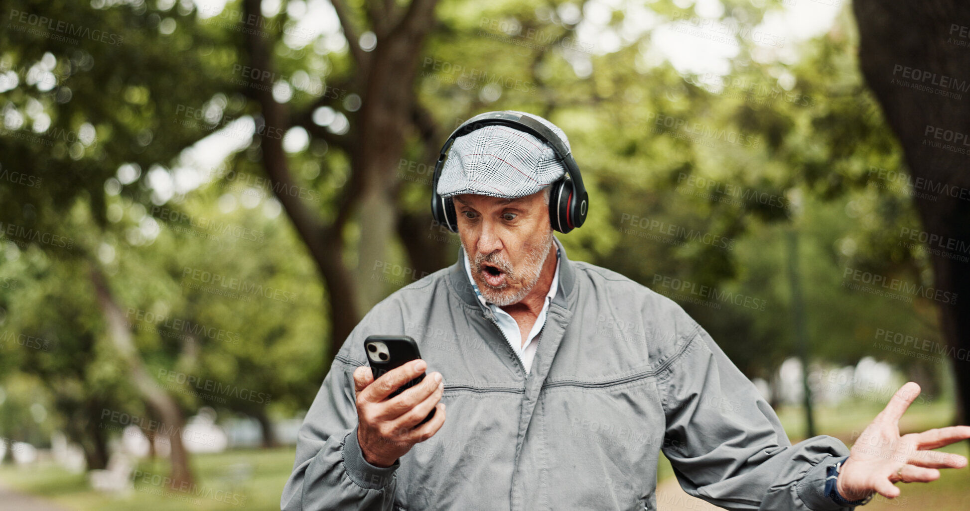 Buy stock photo Headphones, senior man and surprised with phone in park for good news, giveaway winner and gambling bonus. Old person, smartphone and shocked for lottery prize, competition notification and shouting