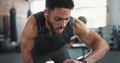 Buy stock photo Man, exercise and check watch at gym for cardio speed, monitor performance and endurance training. Earphones, cycling machine and person listening to music with workout timer for fitness challenge