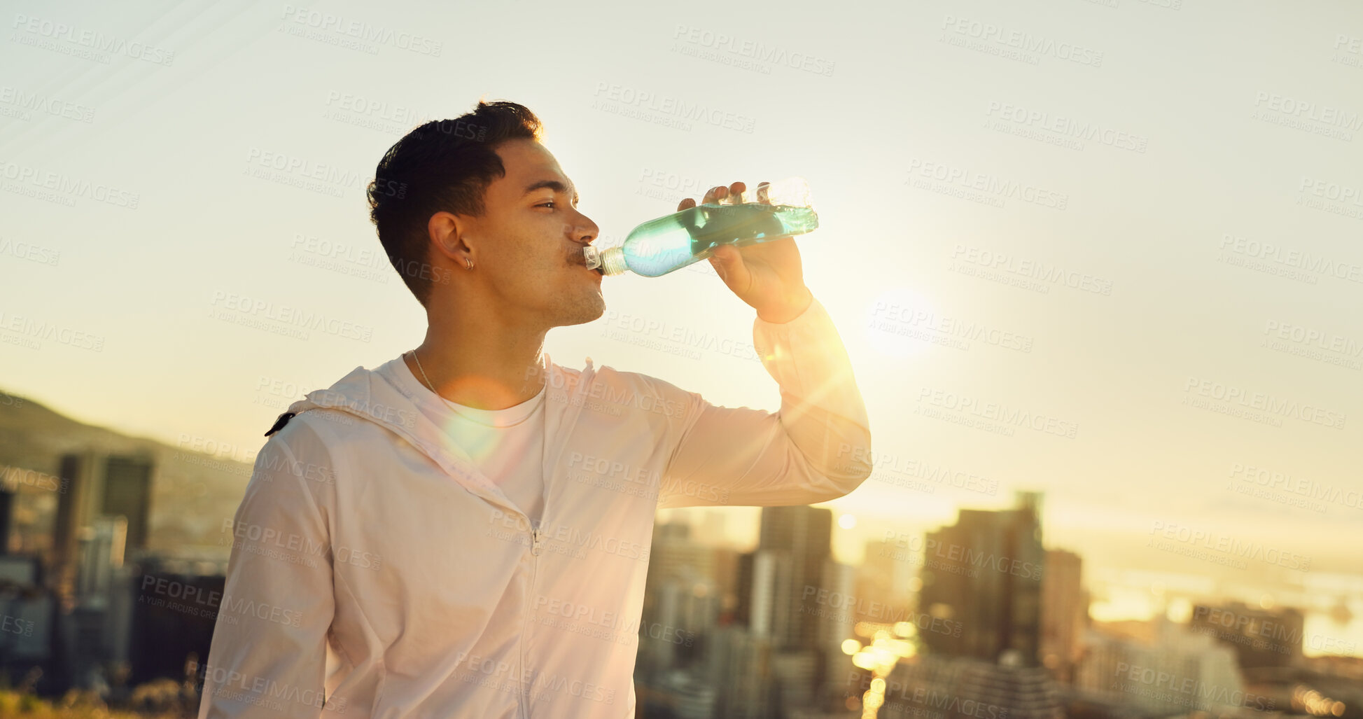 Buy stock photo Athlete, sports drink and sunset with exercise, training and city for fitness or cardio workout. Man, runner and electrolyte hydration on mountain for wellness, health and summer marathon performance