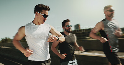 Buy stock photo People, speed and running in city with watch, fitness tracker and check heart rate in urban town. Men, friends support and team blur for movement on street, outdoor cardio and monitor stats or timer