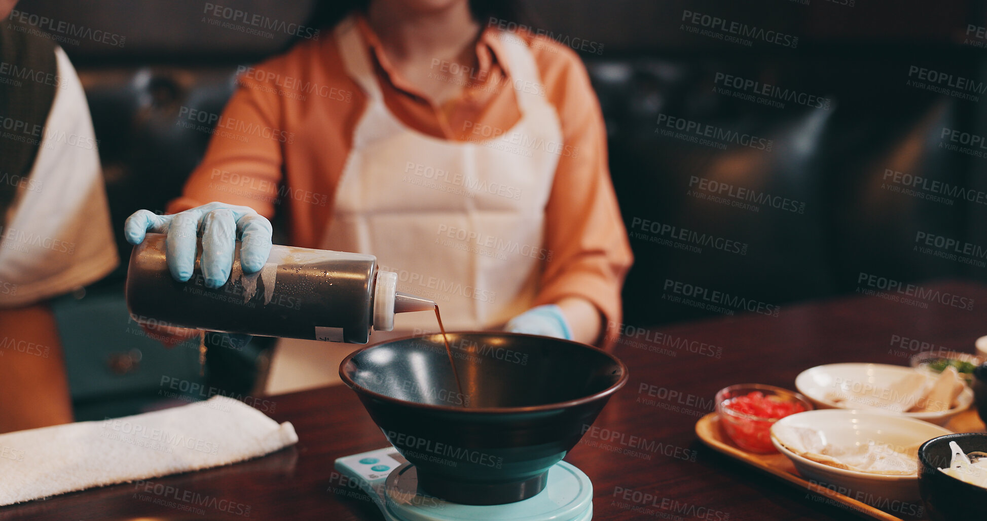 Buy stock photo Restaurant, hands and person with soy sauce for dinner, traditional meal and prepare food for dip. Cafeteria, woman and serving with tsuyu for cuisine, noodles and ramen for culinary culture of Japan