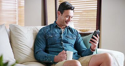 Buy stock photo Man, smartphone and happy with coffee on sofa for texting, chat or reading funny post on mobile app in home. Person, phone and relax with tea cup, drink and smile for contact on social media in house